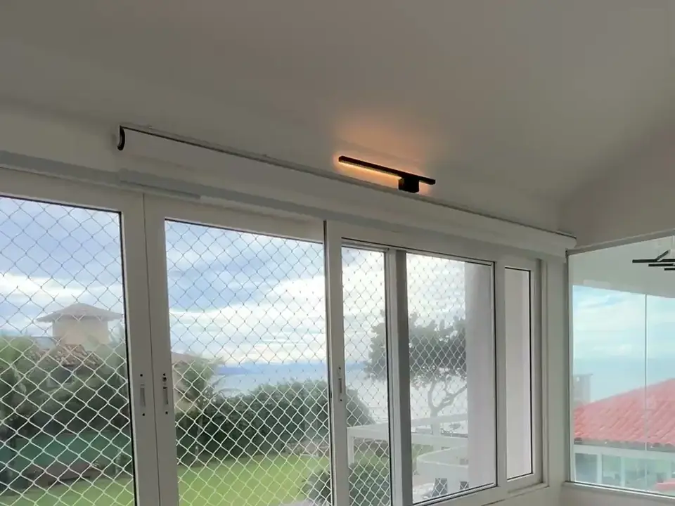 Sala de uma casa com janelas largas, vista para o jardim e a piscina