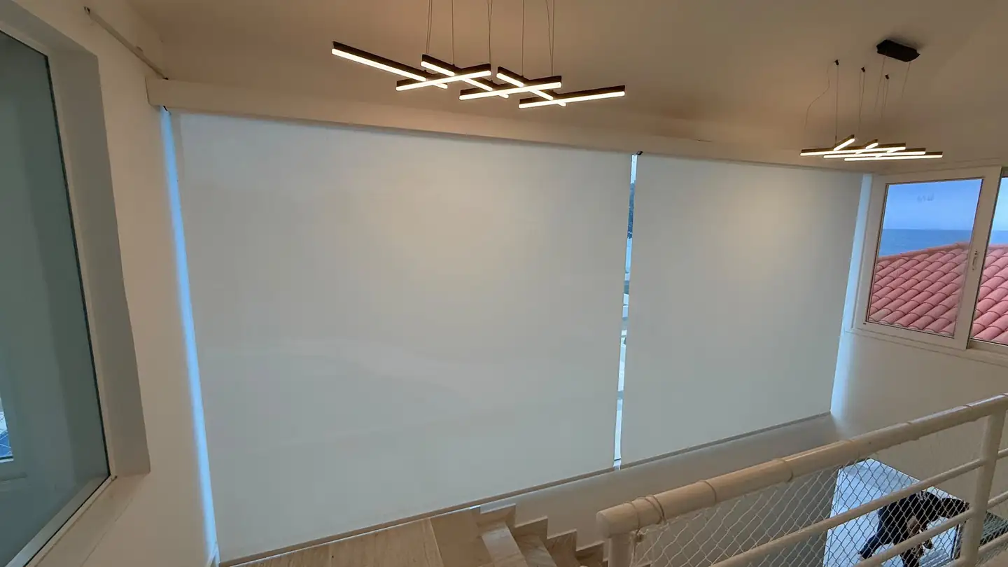 Telas solares fechadas no mezanino de uma casa com vista para o mar