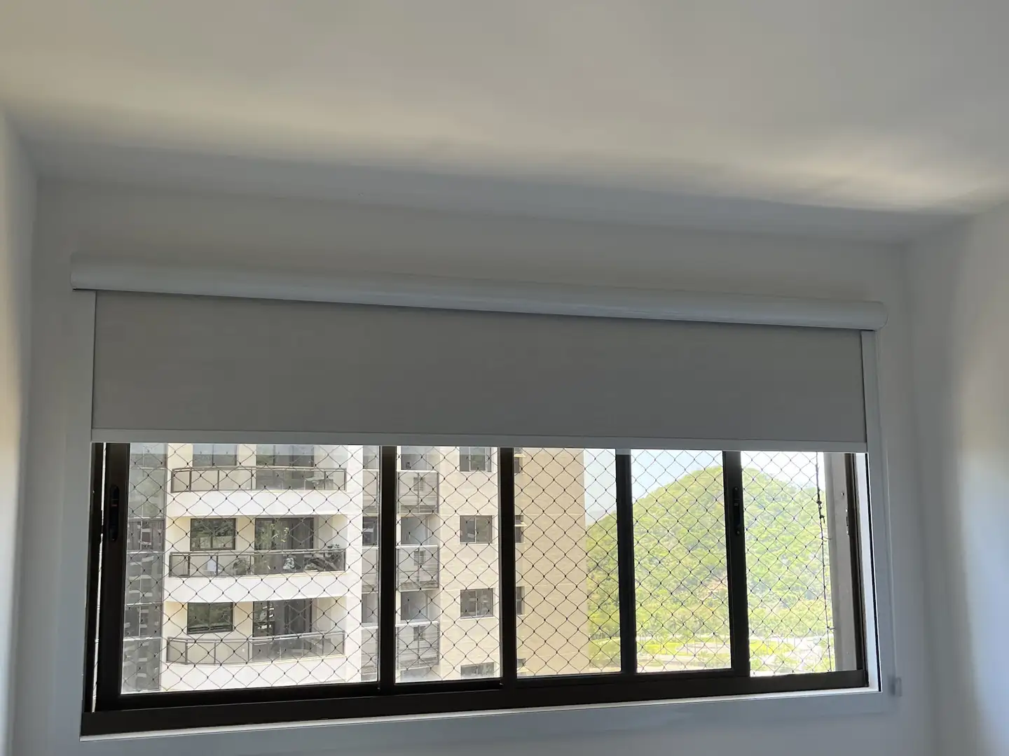 Persianas: quarto com persiana rolô meio fechada sobre uma escrivaninha
