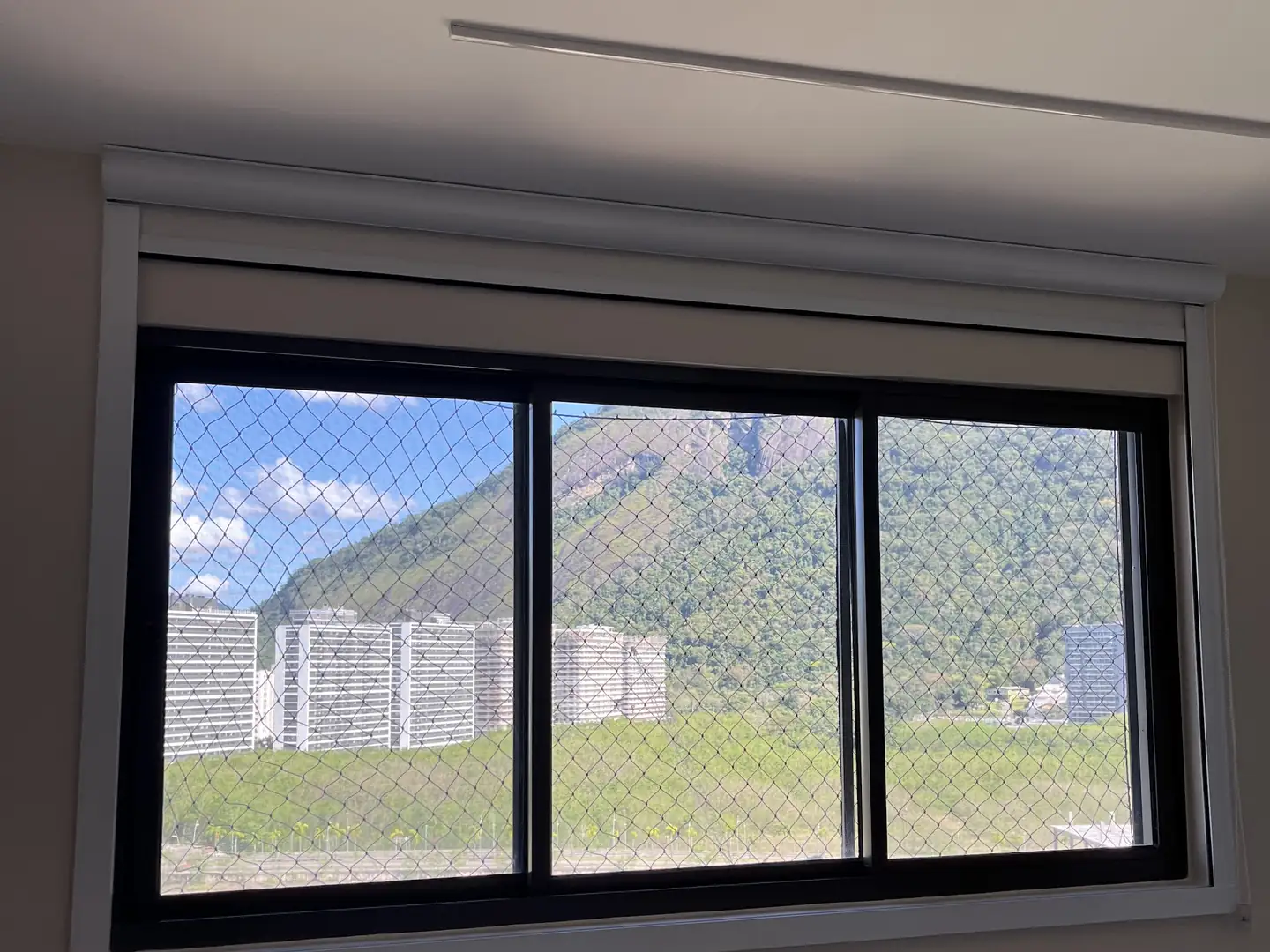 Janela de quarto com persiana rolô recolhida na caixa superior