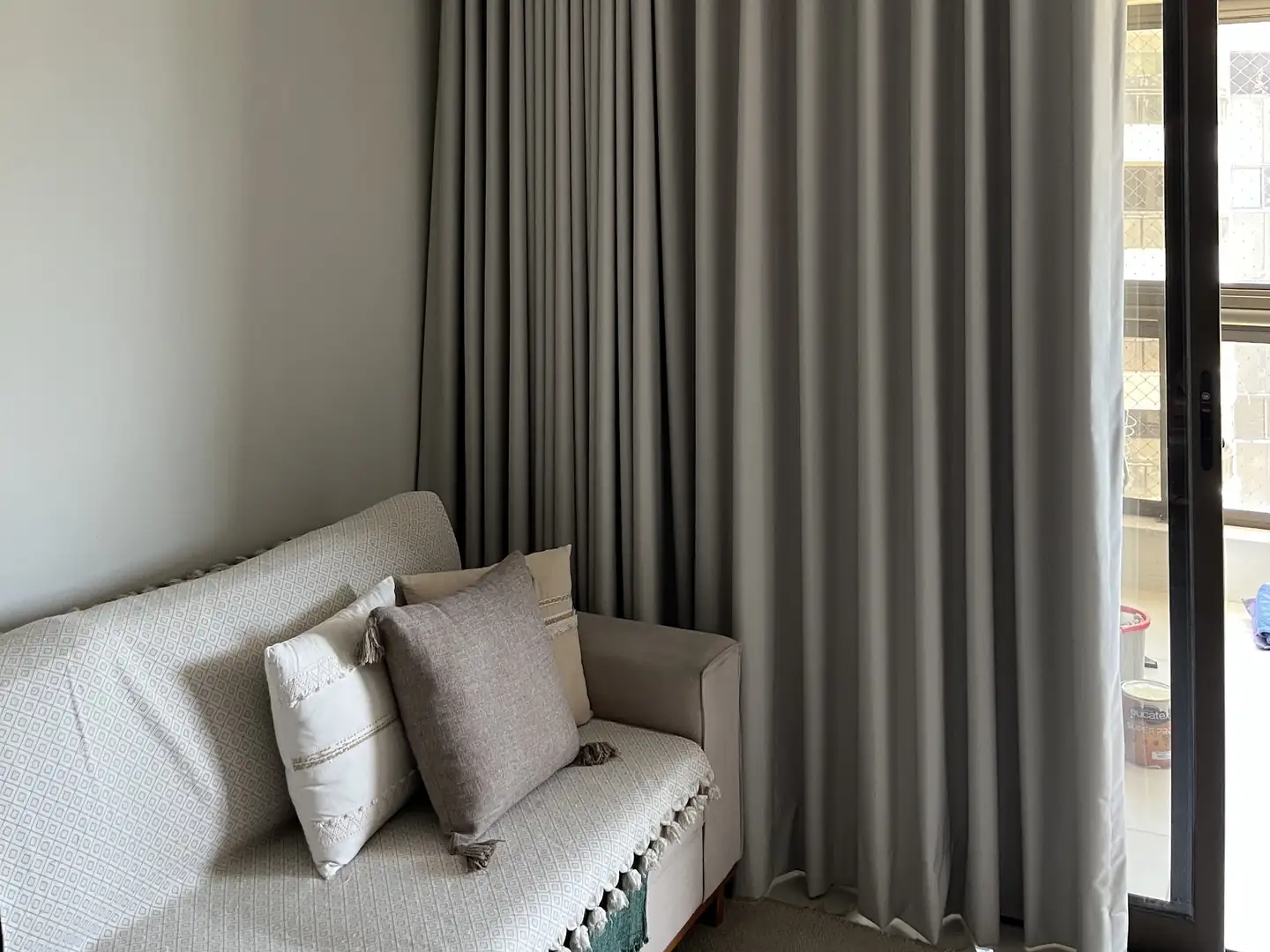 Sala com cortina de tecido cinza recolhida ao lado da porta da varanda