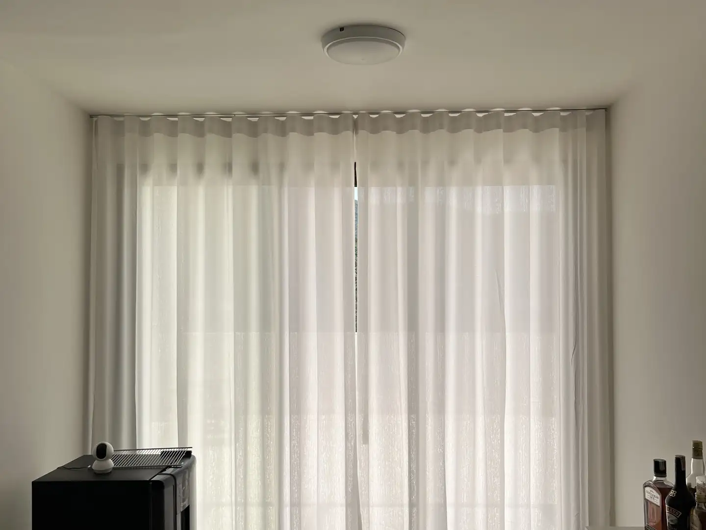 Orçamento de cortinas e persianas: cortina de voil claro fechada, do teto ao piso, em uma sala