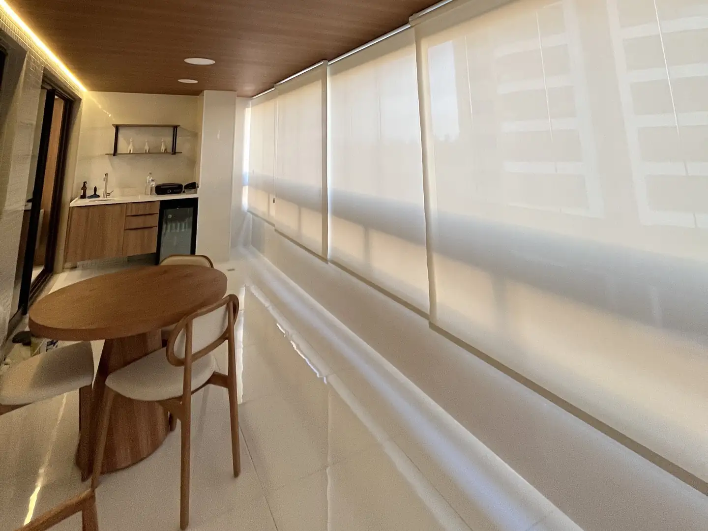 Varanda envidraçada com forro de madeira e telas solares fechadas em toda a extensão