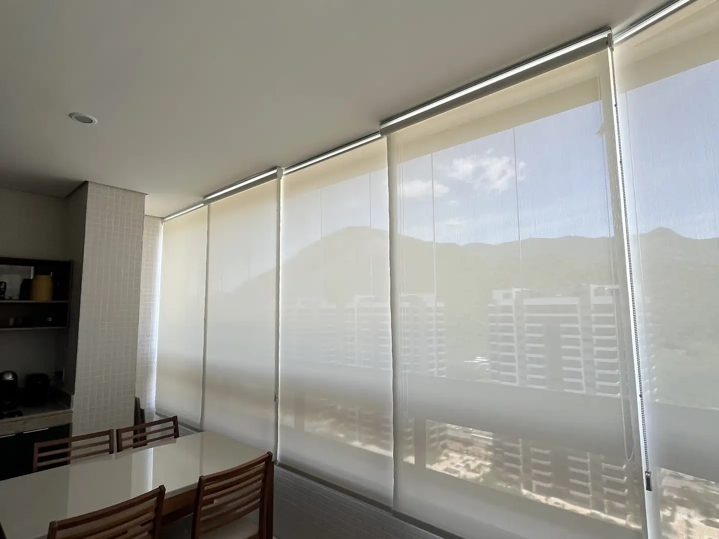 Projeto da Astrale Decor: varanda gourmet com telas solares fechadas e a serra visível através do tecido
