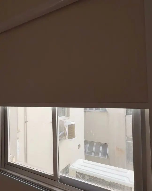 Janela de correr com persiana blackout recolhida até a metade, entre guias de alumínio