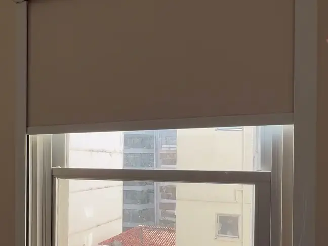 Persiana rolô blackout com guias laterais descendo sobre uma janela de quarto