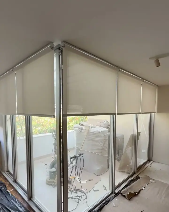 Telas solares motorizadas no Leblon: telas solares começando a descer, alinhadas, em um canto envidraçado