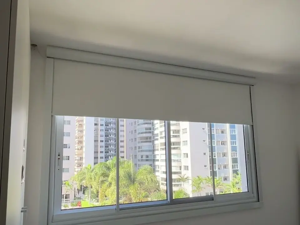 Persiana rolô blackout com guias laterais a meia altura em uma janela de quarto