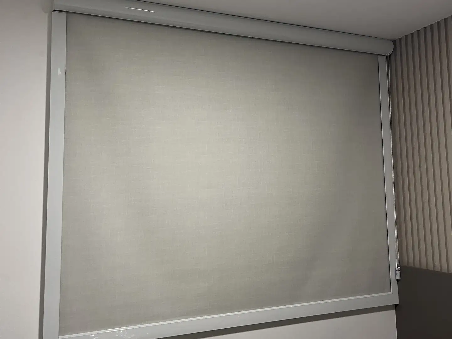 Quarto com persiana rolô fechada cobrindo toda a janela