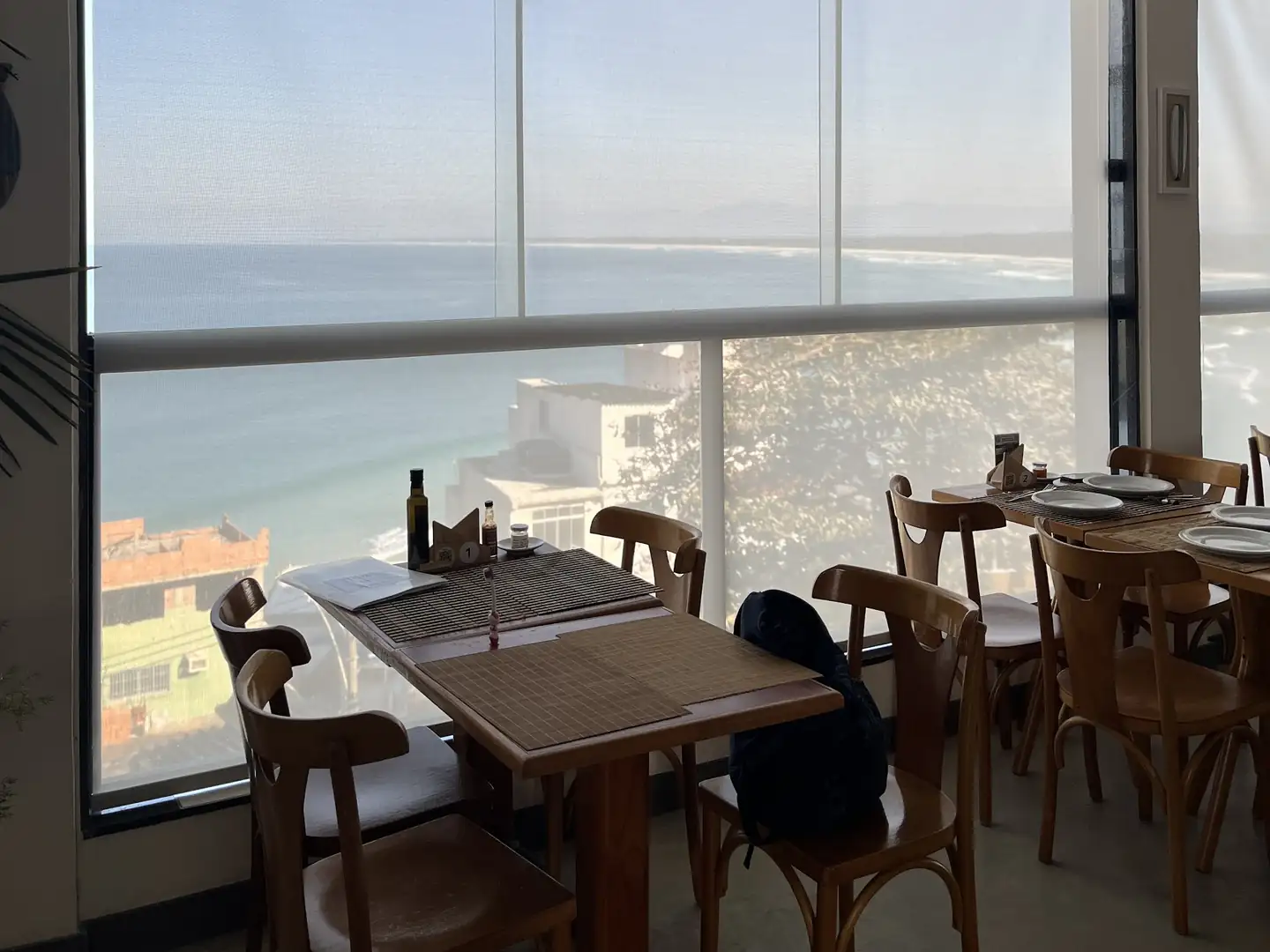 Salão de restaurante com telas solares meio fechadas e vista para o mar