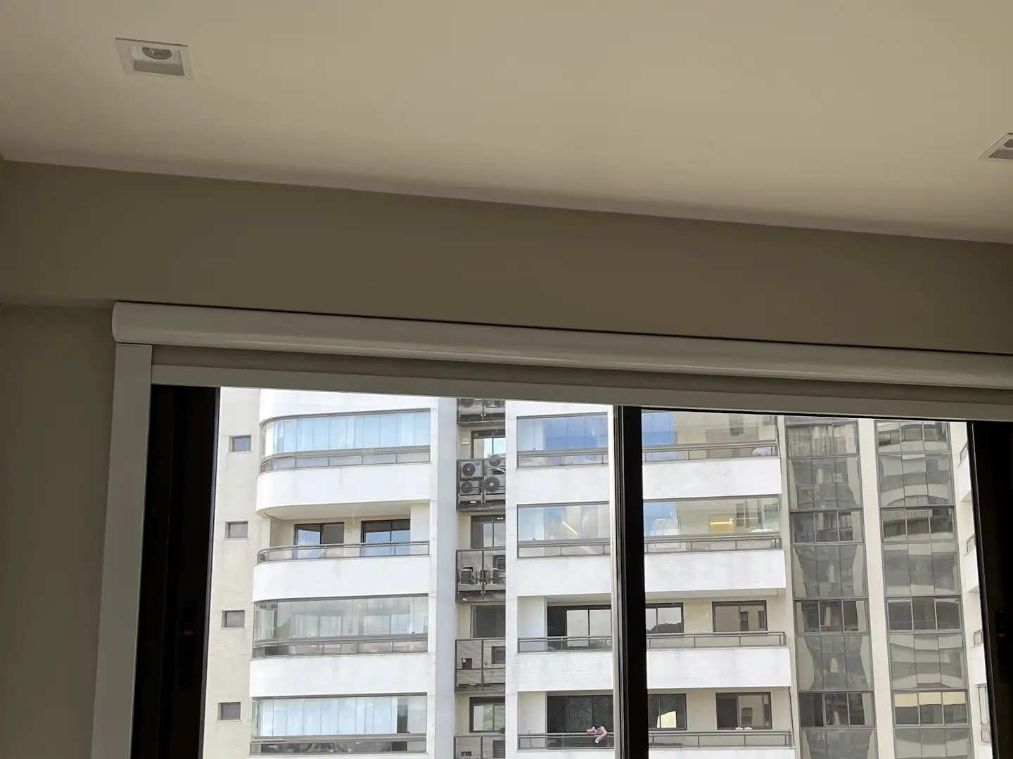 Persiana rolô blackout com guias laterais recolhida, com a janela livre