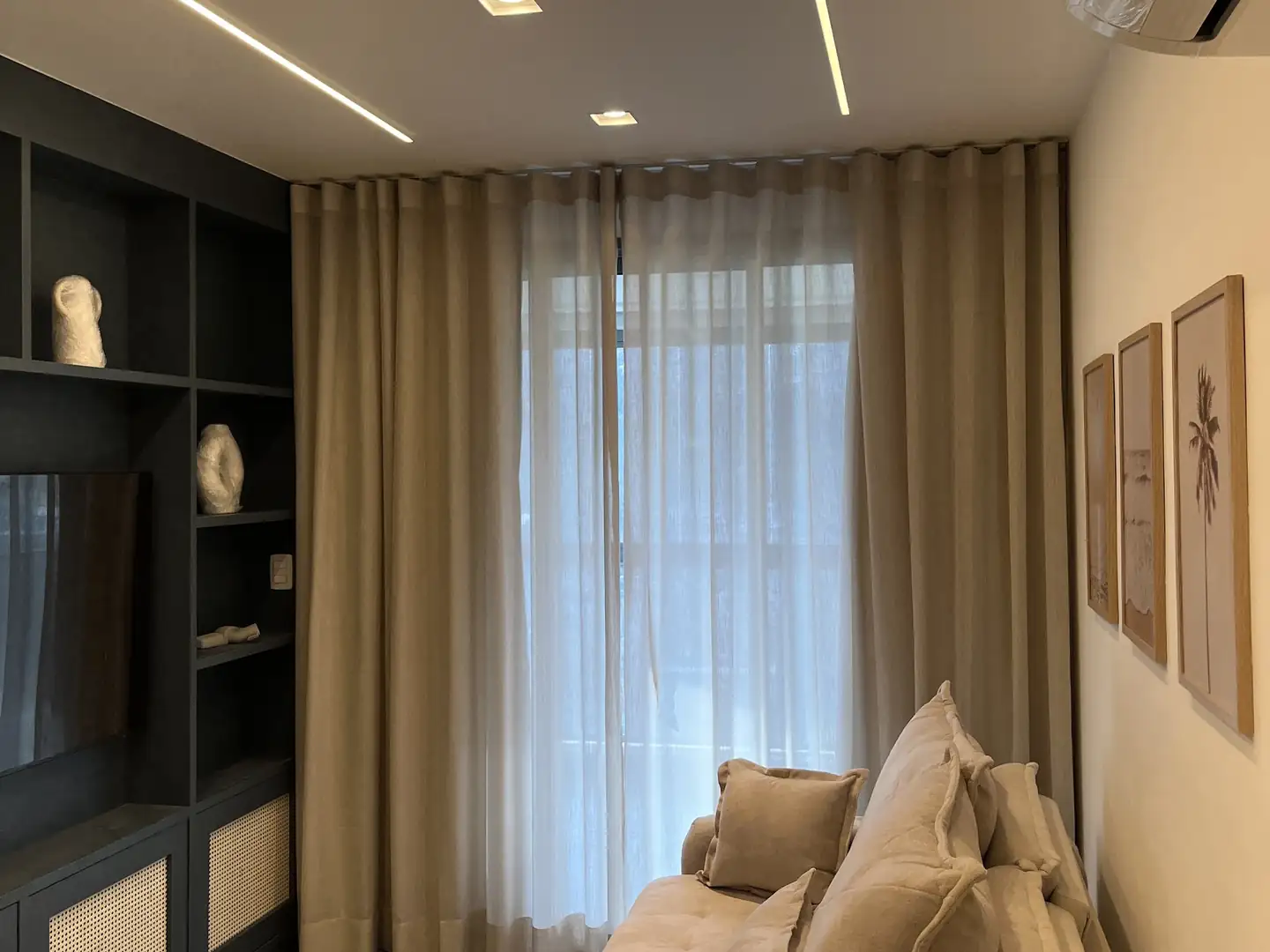 Sala com cortina wave em tom areia aberta sobre o voil, com sofá e estante