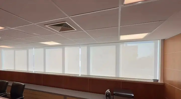 Sala de reunião com painéis de madeira e telas solares fechadas em toda a faixa de janelas