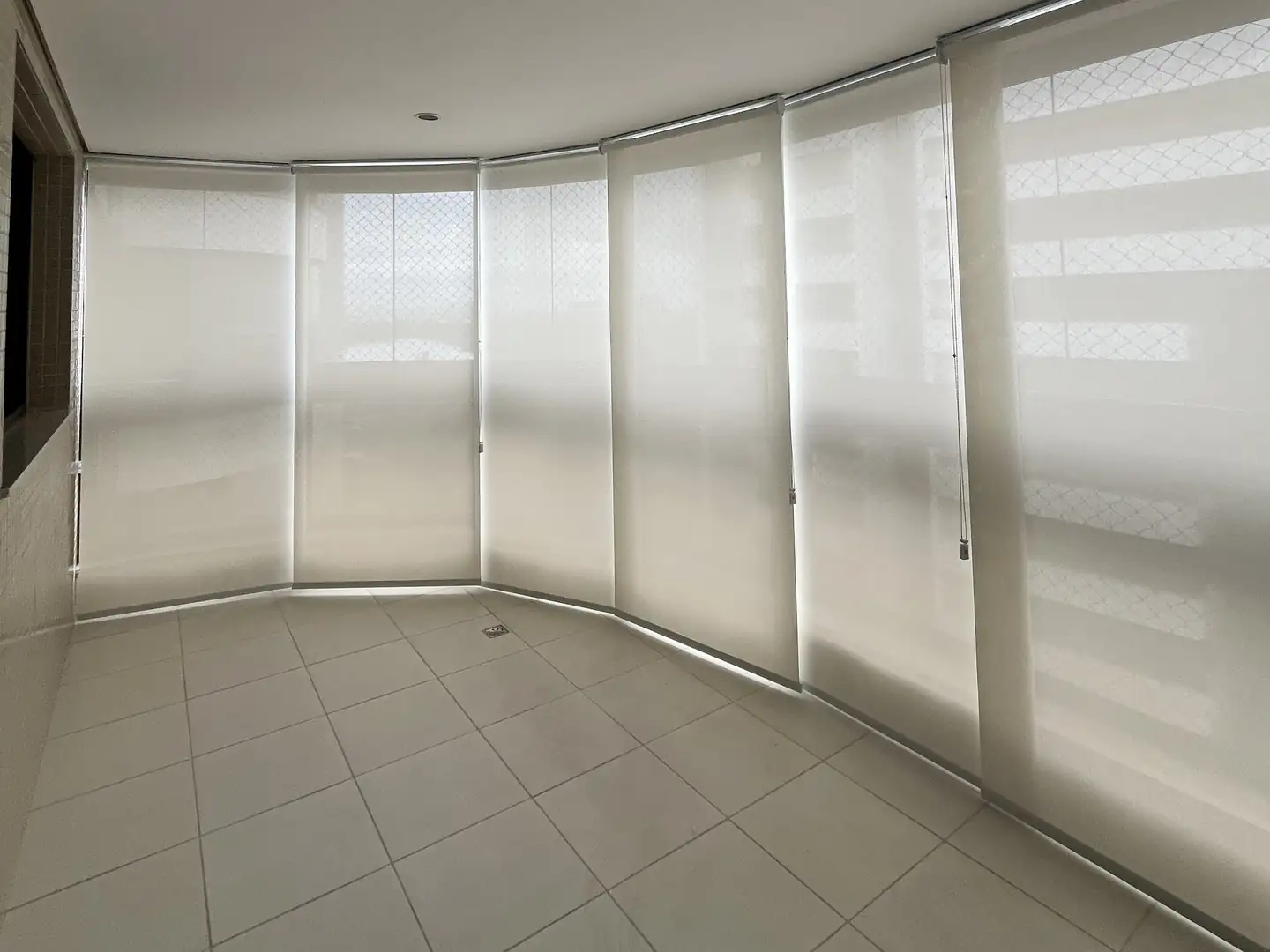 Varanda curva com telas solares fechadas em todos os vãos. Projeto da Astrale Decor